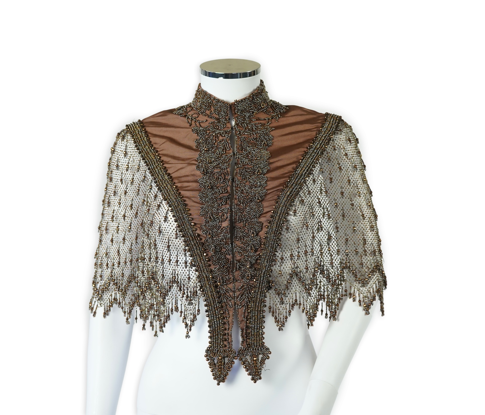 A late 19th century ladies ornate steel and brown beaded and fringed shoulder cape. Made as three ribbed silk panels with ornate beaded appliqués with a beaded and fringed net sleeved cape. Top of neck to bottom of beadi